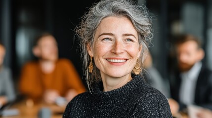 Mature caucasian female smiling in a black sweater in office meeting setting