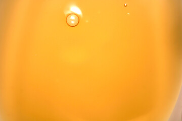 Close-Up View of Orange Liquid with Bubbling Drop on Surface