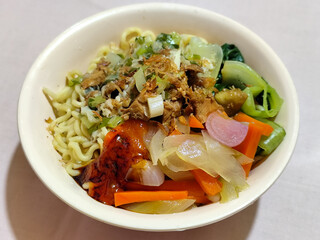 A bowl of delicious chicken noodles, complete with claws, dumplings, chicken pieces on top, traditional Indonesian food.