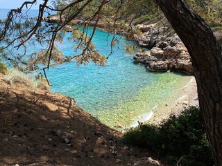 A view of a small beach with white stones, rocks and clear blue water of the Mediterranean Sea near Kemer, Antalya, Turkey in sunny weather. Little white bay.