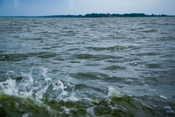 Fototapeta premium Vast expanse of open water with gentle waves and distant shoreline under a soft sky