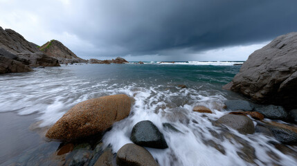 A tranquil composition of gentle waves lapping at serene rocks, evoking a sense of peace and tranquility against the backdrop of a moody, overcast sky.