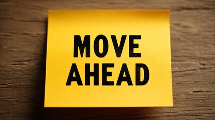 Motivational yellow sticky note with inspirational message 'move ahead' on wood