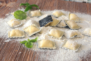Homemade ravioli with basil leaves on wooden board. Healthy food and organic products.