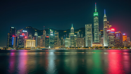 Fototapeta premium Stunning city skyline at night with illuminated skyscrapers reflecting on water, showcasing modern architecture and vibrant lights