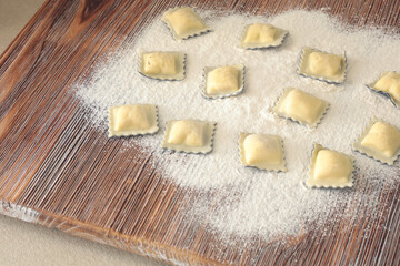 Homemade ravioli with fish and cuttlefish ink on wooden board. Traditional food, Italy. Healthy eating and organic products.