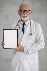 Doctor in a white coat smiling and holding a tablet in a clinical setting, ready to share information with patients