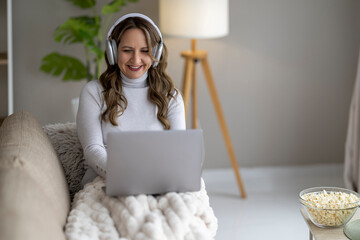 Enjoying a cozy evening at home while watching a movie on a laptop with popcorn nearby