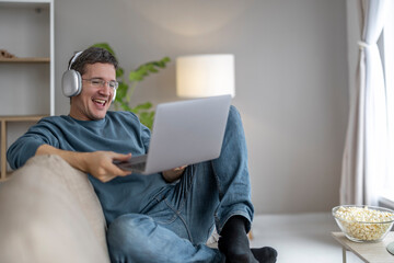 Man enjoying a movie at home with popcorn and headphones on a cozy evening