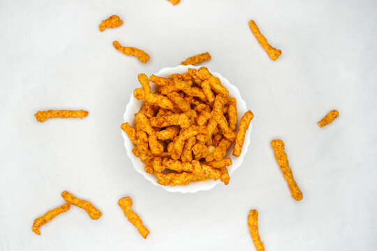 Delicious India favorite snack kurkure crunchy corn sticks, on white background. Indian tea snacks concepts.