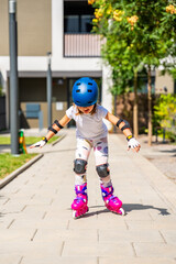 Little girl learning to roller skate for the first time at the age of five. Concept of physical development, balance training and childhood independence through active play.