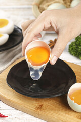 Fresh Raw Duck Egg Yolk Separation in Kitchen Cooking Preparation with Clear Eggshell and Black Bowl