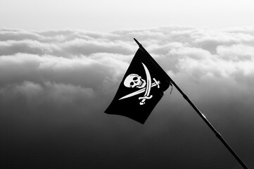 Jolly Roger - pirate flag on wind and sea in cloudy sky