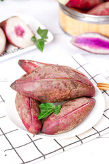 Raw Purple Sweet Potatoes with Pink Heart Center and Mint Garnish on White Plate