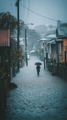 A solitary figure with an umbrella walks down a rain-soaked street, the houses on either side blurred by the downpour.  The atmosphere is moody and atmospheric