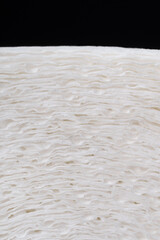 A close-up of a roll of white paper with a distinct texture and three layers of fibers.