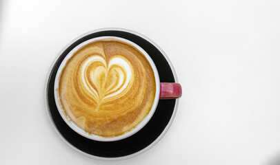 A cup of cappuccino with heart-shaped foam on a light background, top view