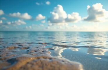 Calm ocean water with sandy shoreline under a bright blue sky with fluffy clouds