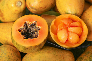 Fresh Cut Papaya with Seeds and Orange Flesh Among Whole Tropical Fruits