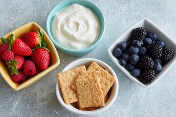 Fresh strawberries, blueberries, blackberries, and yogurt served in colorful bowls with whole grain crackers on a textured surface, showcasing healthy snack options and vibrant colors