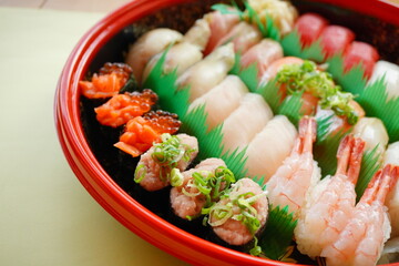 A beautifully arranged assortment of traditional Japanese sushi with fresh seafood including shrimp, salmon, tuna, and ikura, served in a festive round tray