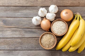 Fresh ingredients including bananas, onions, garlic, and bowls of rice and oats arranged on rustic wooden surface, showcasing healthy cooking essentials with copy space