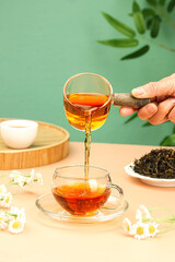 Freshly Brewed Tea Being Poured from Glass Teapot with Dried Leaves and Flowers