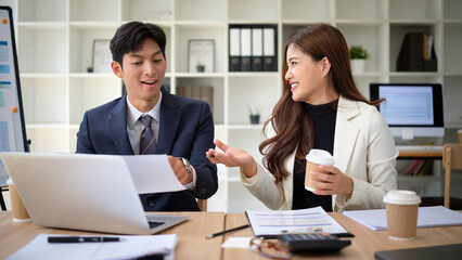 Two young professionals discuss business strategies over documents and coffee.