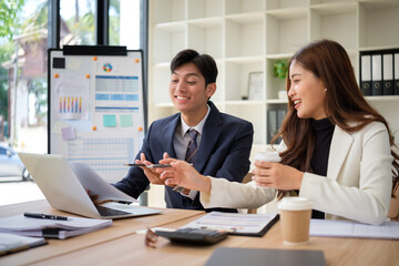 Two young professionals smile and collaborate during a casual meeting in a bright office.