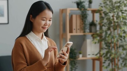 Asian businesswoman using smartphone in modern office with plants, digital communication and mobile productivity - Powered by Adobe