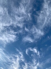 Blue sky with white cirrus clouds on a clear day. Natural background of soft cloudscape