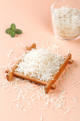 White rice grain in wooden tray with bowl and mint on pink background, shallow depth of field food photography