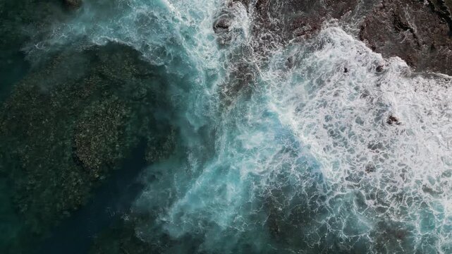 Aerial view of rocky, volcanic shoreline and foamy ocean waves flooding the seaside coast, Tenerife, Canary Islands, Spain.