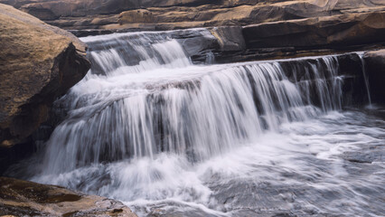 waterfall with foamy texture surrounded with rocks and mountains