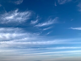 Blue sky with white cirrus clouds on a clear day. Natural background of soft cloudscape