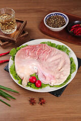 Fresh Raw Pork Belly with Thick Skin on White Plate Ready for Cooking with Spices and Garnish