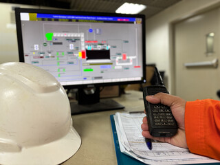 Industrial monitoring workstation with safety equipment and handheld communication tool depicting process control displayed on monitor showcasing a modern industrial setting and operational technology