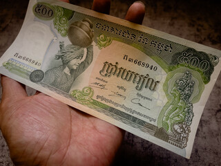 Hand holds a cambodian 500 riel banknote.