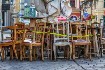 Row of vintage wooden chairs tied with yellow tape in outdoor cafe