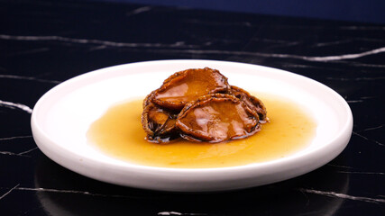 Dalian Style Abalone Seafood Dish with Cucumber and Golden Sauce on White Plate
