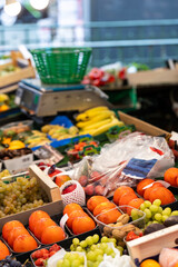 Fresh fruits and nuts, including kish-mish grapes, walnuts, persimmons, mangoes, lychees, white grapes, and strawberries, are for sale at a street market in Paris, France.