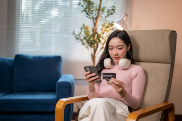 Young woman shopping online using smartphone and credit card at home