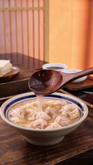 Homemade Pork Wonton Soup with Clear Broth Being Served in Traditional Bowl