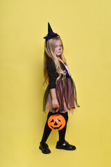 Little girl with blonde hair in a witch costume with a candy cane for Halloween
