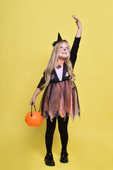 Little girl with blonde hair in a witch costume with a candy cane for Halloween