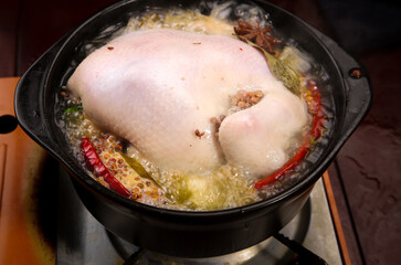 Fresh Whole Free Range Chicken Cooking in Spiced Broth with Vegetables and Herbs