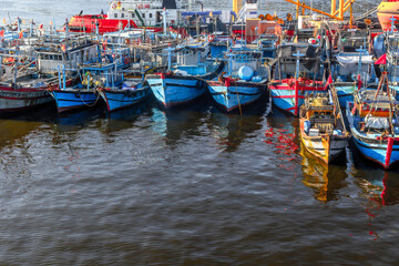 Colorful fishing boats moored in a busy harbor at sunset
