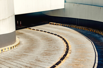Curved concrete driveway ramp with yellow safety markings in urban parking facility