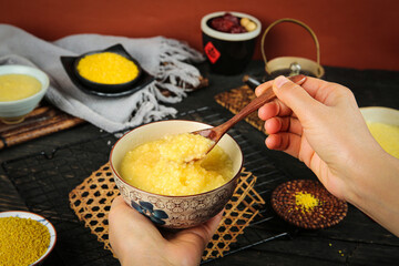 Traditional Yellow Millet Congee Porridge Breakfast from Shanxi China with Wooden Spoon and Raw Grains