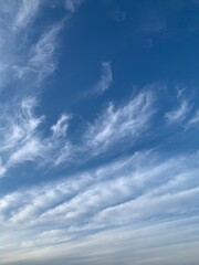 Blue sky with white cirrus clouds on a clear day. Natural background of soft cloudscape